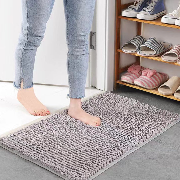 Person stepping onto a gray rug with shoes and slippers on a shelf in the background.