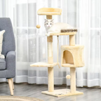 Cat sitting on a multi-level cat tree in a room with a gray armchair and white curtains.